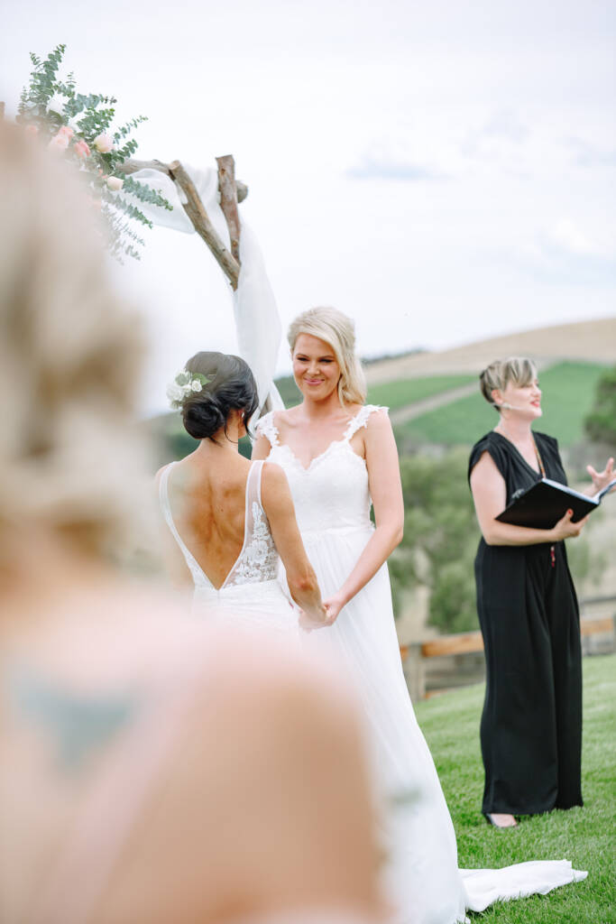 Kate smiles at Ashlee as the celebrant addresses guests beside the vineyard at Riverstone.