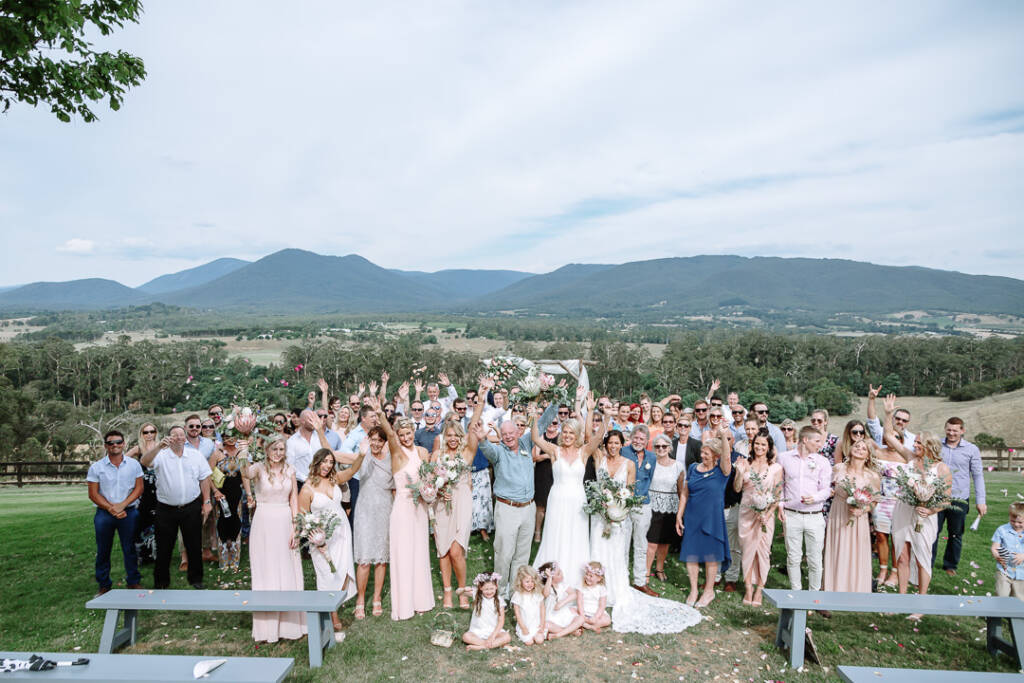 Ashlee, Kate and their guests cheer for a group photo on the lawn at Riverstone Estate in the Yarra Valley.