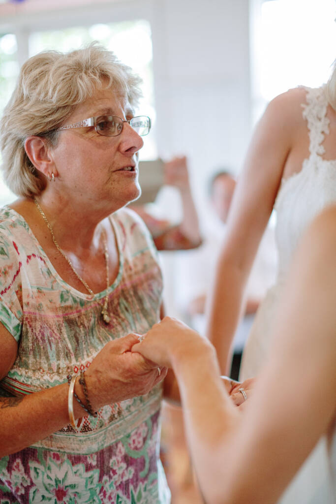 A guest holds a bride's hand while talking with Ashlee and Kate during the reception.