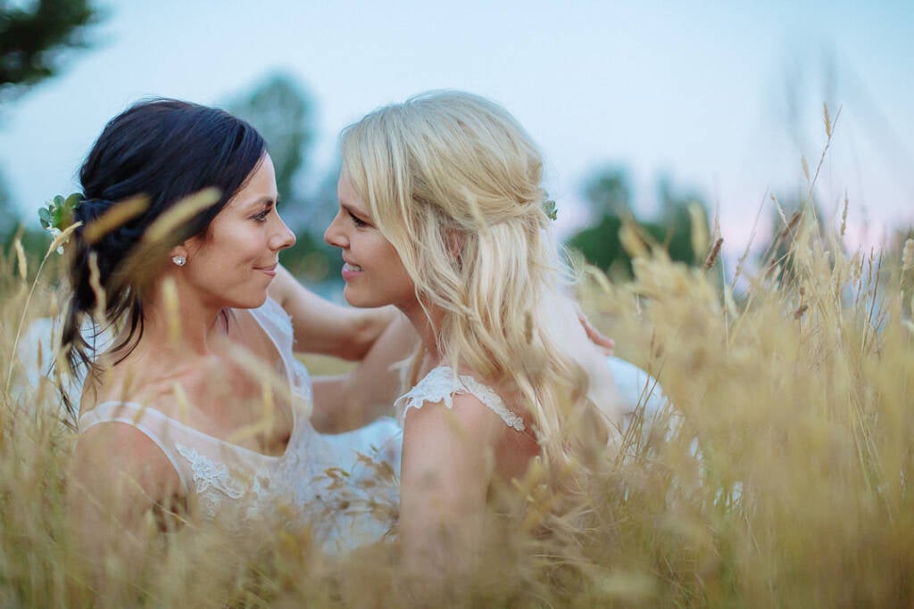 Ashlee and Kate sit close together among the tall grasses at Riverstone in the evening light.
