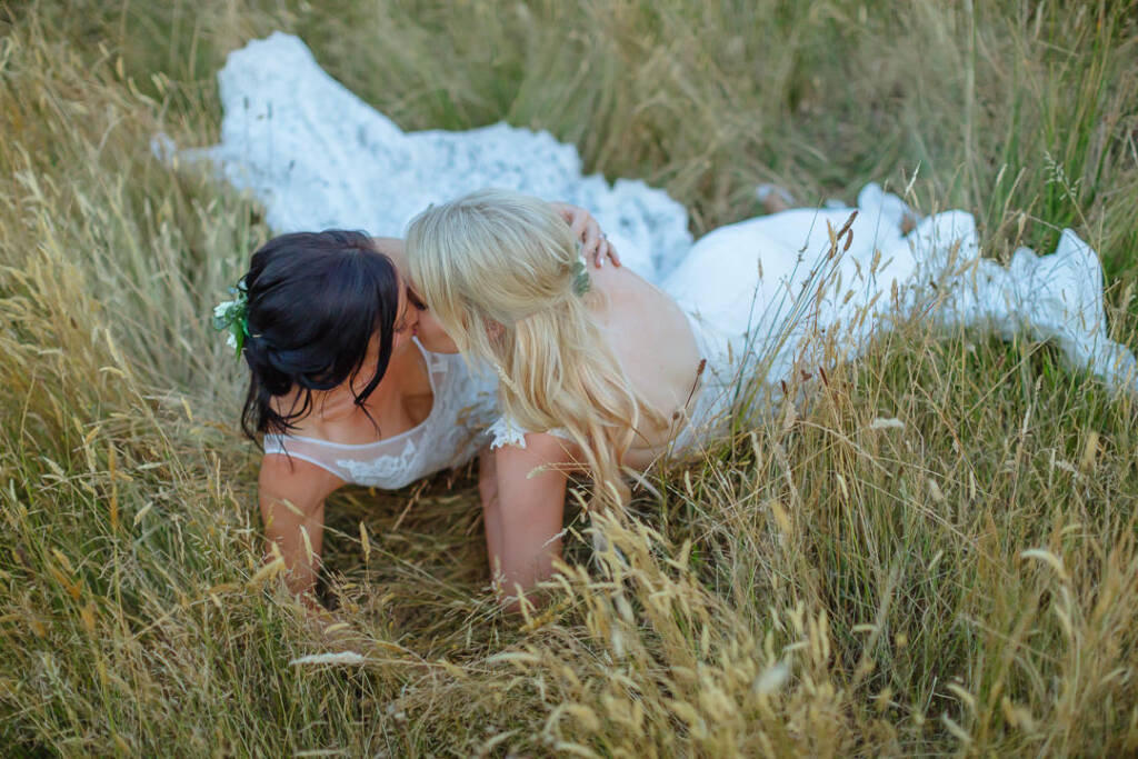 An overhead portrait shows the couple kissing with their gown trains spread in the grass at Riverstone Estate.