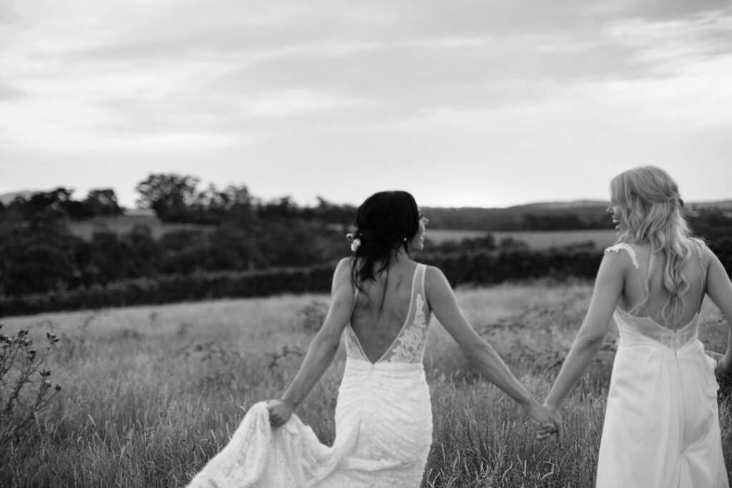 Black-and-white portrait of the couple walking hand in hand through the paddock at Riverstone Estate.