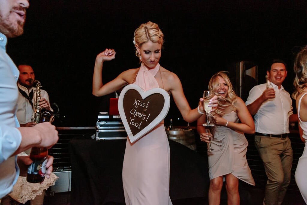 An attendant dances wearing a heart-shaped chalkboard sign during the Riverstone Estate reception.