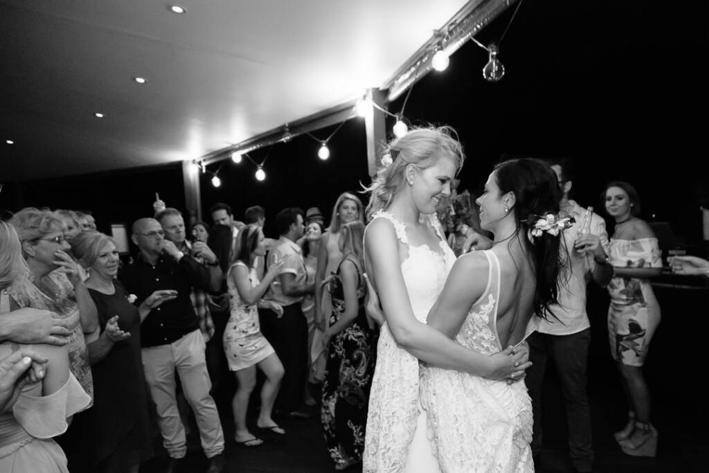 Black-and-white photo of Ashlee and Kate dancing in close hold among guests at Riverstone.