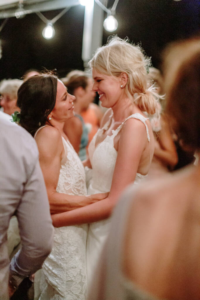 Ashlee and Kate smile at each other while dancing beneath the festoon lights at Riverstone Estate.