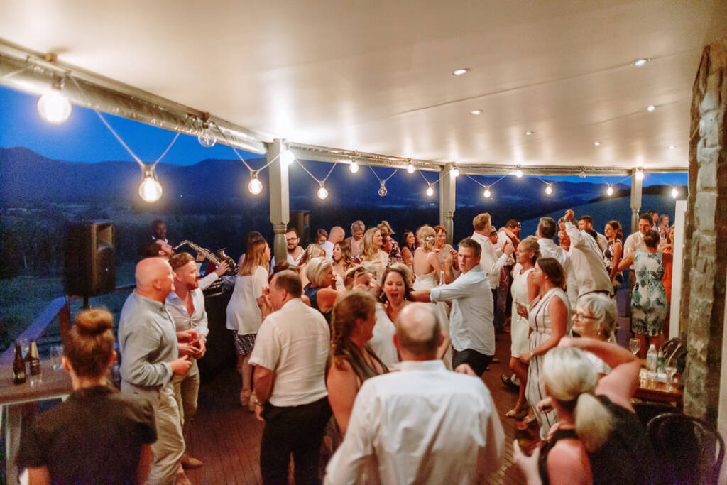 Guests fill Riverstone's verandah dance floor beneath festoon lights beside the bluestone homestead.