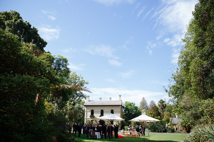 Guests gather beneath market umbrellas on the lawn in front of Gardens House before the ceremony.