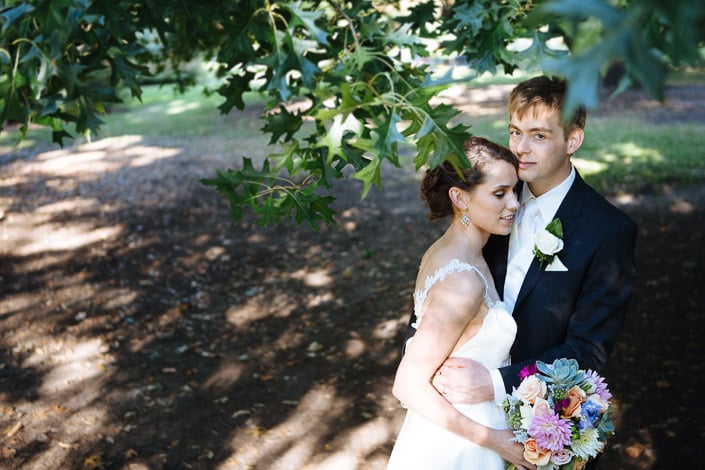 Frances and Tim in dappled shade beneath an oak branch at Royal Botanic Gardens Melbourne.