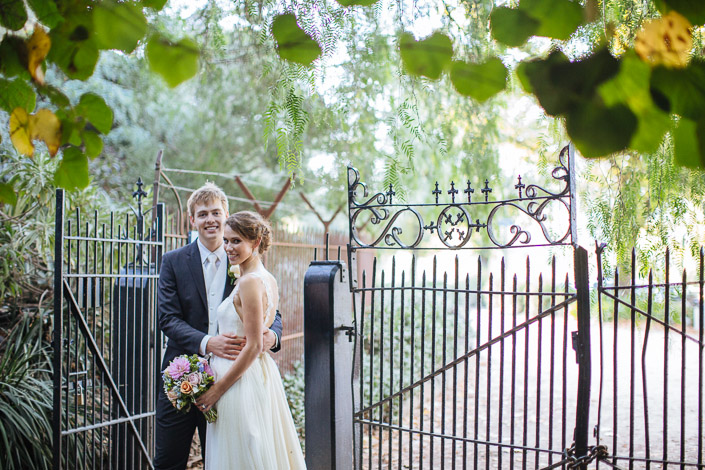 Frances and Tim lean together at an ornate wrought iron gate in the Royal Botanic Gardens.