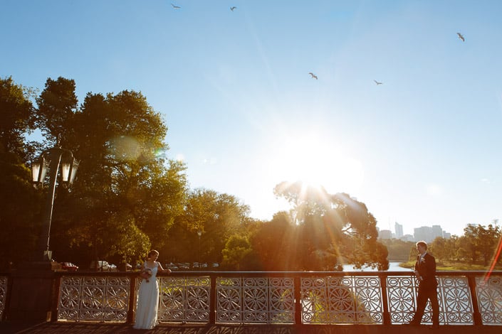 At opposite ends of Morell Bridge, Frances and Tim look out with the Melbourne skyline behind.