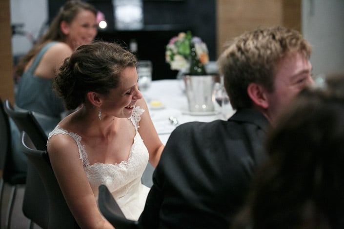 Frances throws her head back laughing at the reception table beside Tim.