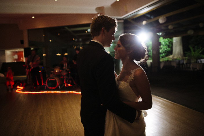 Frances and Tim share their first dance as a live band plays behind a rope of orange lights.