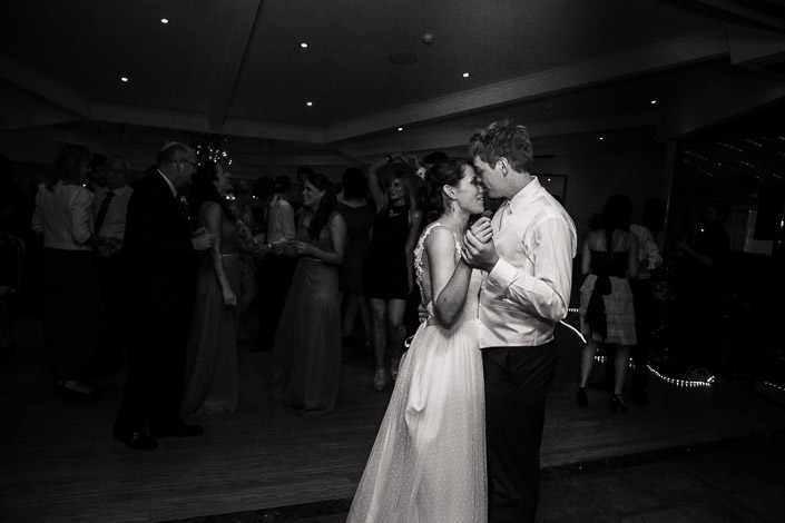Black and white photo of Frances and Tim dancing cheek to cheek as the room fills.