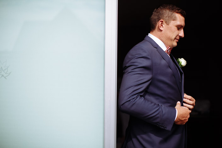 A pause at the frosted door, hand settling the lapel