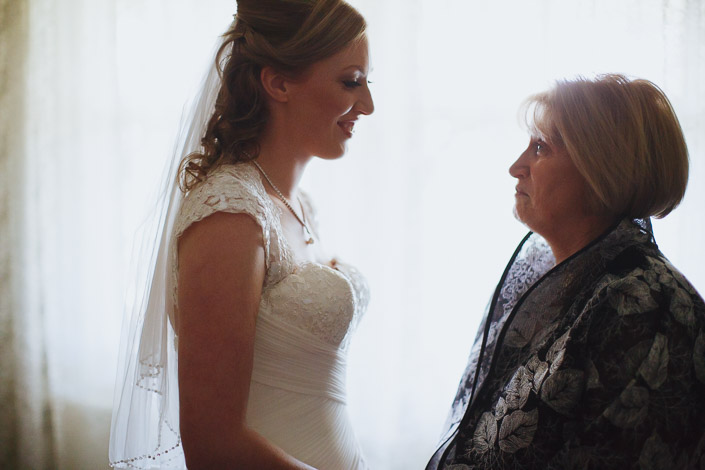 A long look between the bride and a woman in a leaf print jacket at the window.
