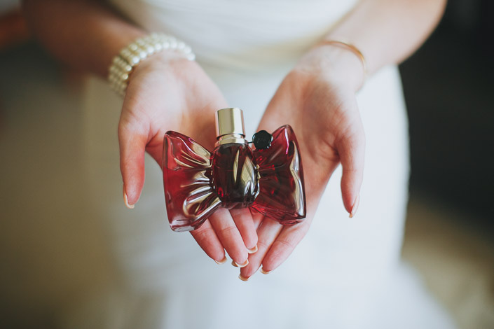 A bow-shaped perfume bottle cradled in both palms
