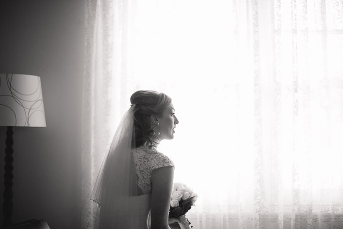 A monochrome silhouette at the lace curtains, roses in hand