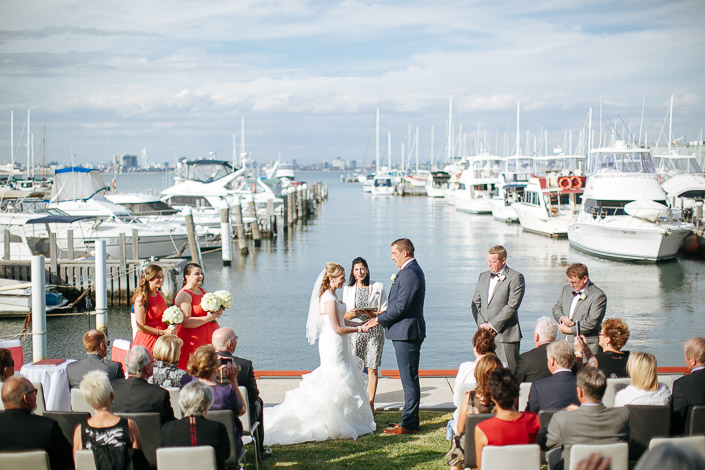 Vows on the marina edge, the city faint across the bay
