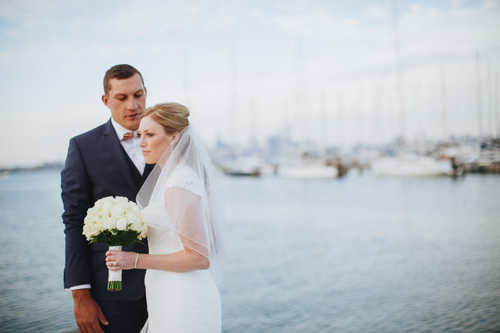A quiet moment above the water, the rose bouquet between the bride and groom.