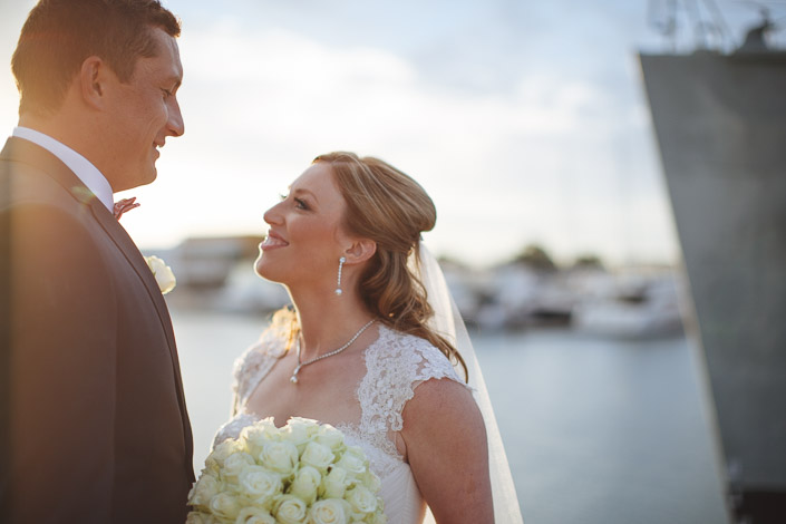 The bride looks up at the groom mid laugh in the golden hour glow.