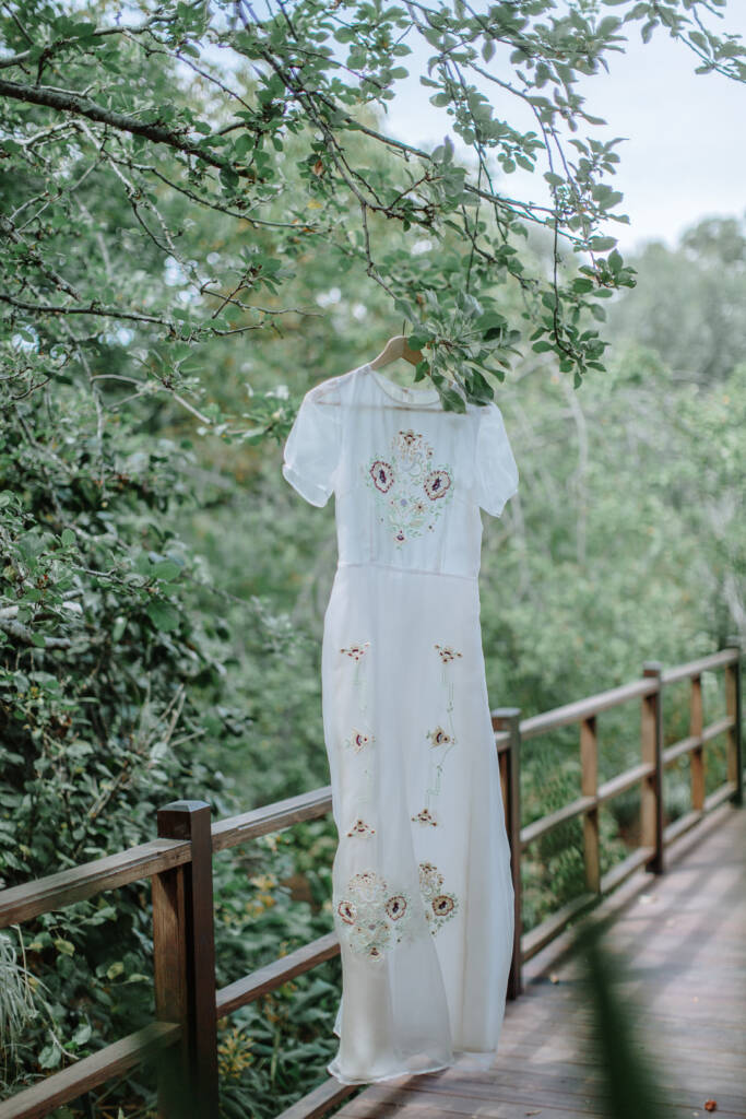 Sarah's embroidered wedding gown hangs from a branch beside the timber railing at Strathvea Guesthouse.