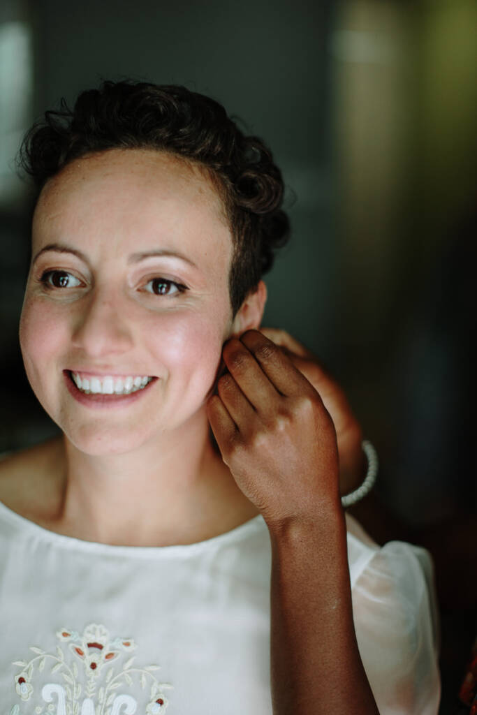 Close-up of Sarah smiling while a helper adjusts her earring.