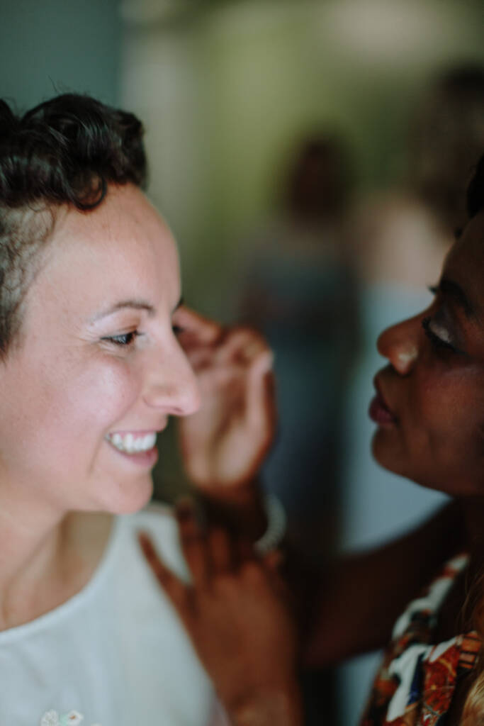 Sarah smiles in profile as a helper attends to her earring.