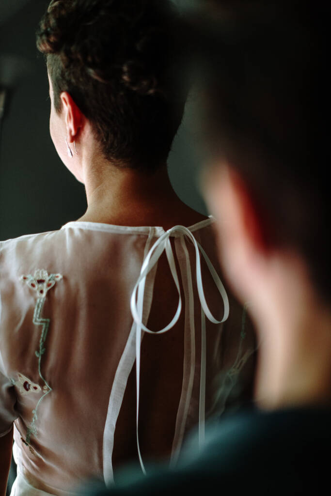 The tied ribbon and sheer embroidered back of Sarah's short-sleeved wedding gown.