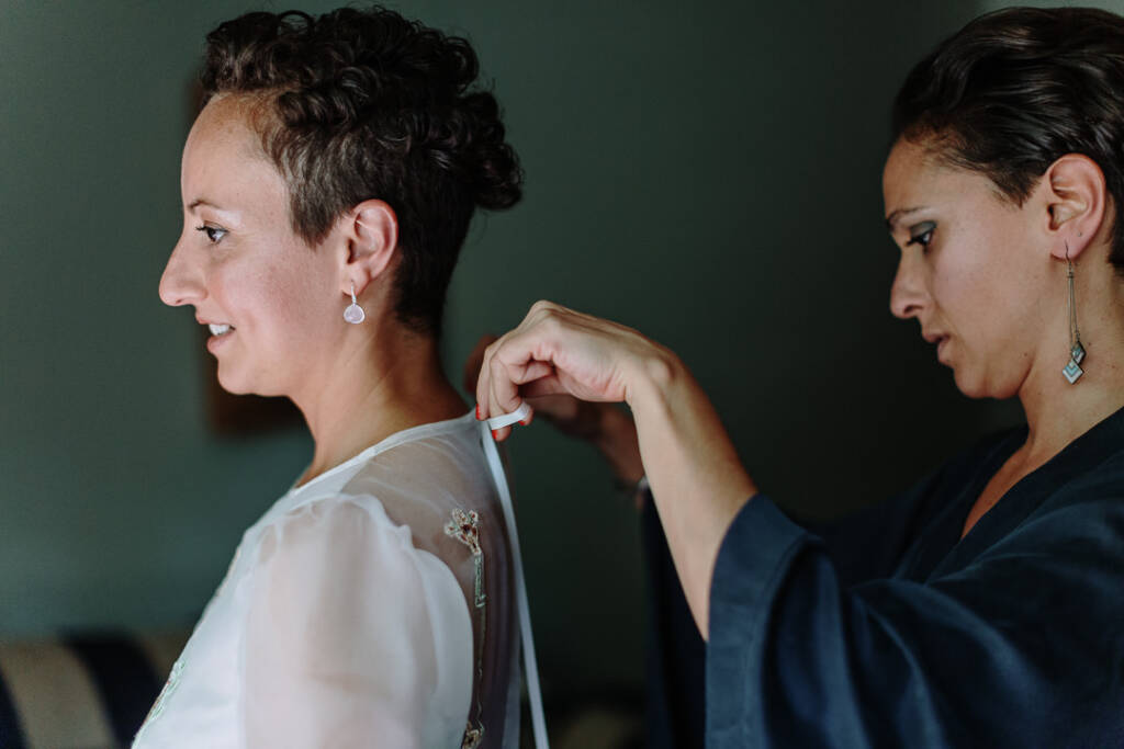A helper adjusts the ribbon at the back of Sarah's neckline.