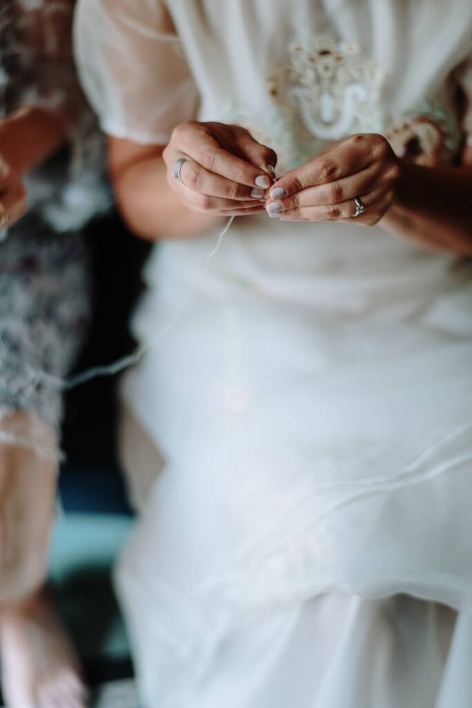 Close-up of Sarah handling white thread during the finishing touches to her wedding outfit.