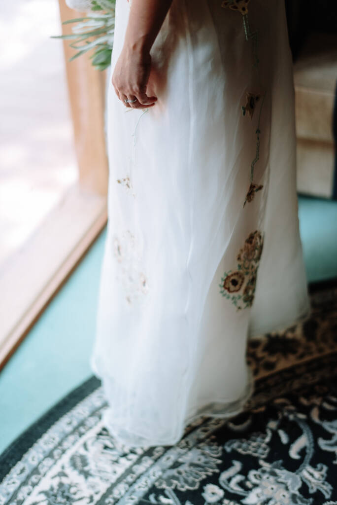 Close-up of the embroidery on Sarah's wedding gown beside a patterned rug at Strathvea.