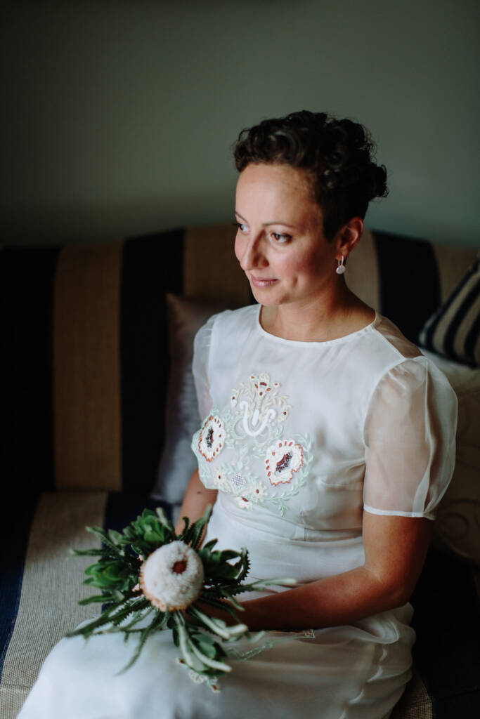 Sarah sits with her banksia bouquet on a striped sofa at Strathvea.