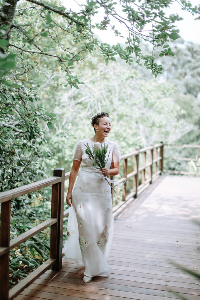 Sarah laughs with her bouquet on the timber verandah at Strathvea Guesthouse.