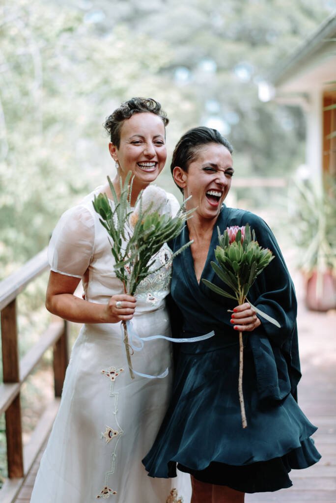 Sarah and an attendant laugh together with banksia and protea bouquets on the verandah at Strathvea.