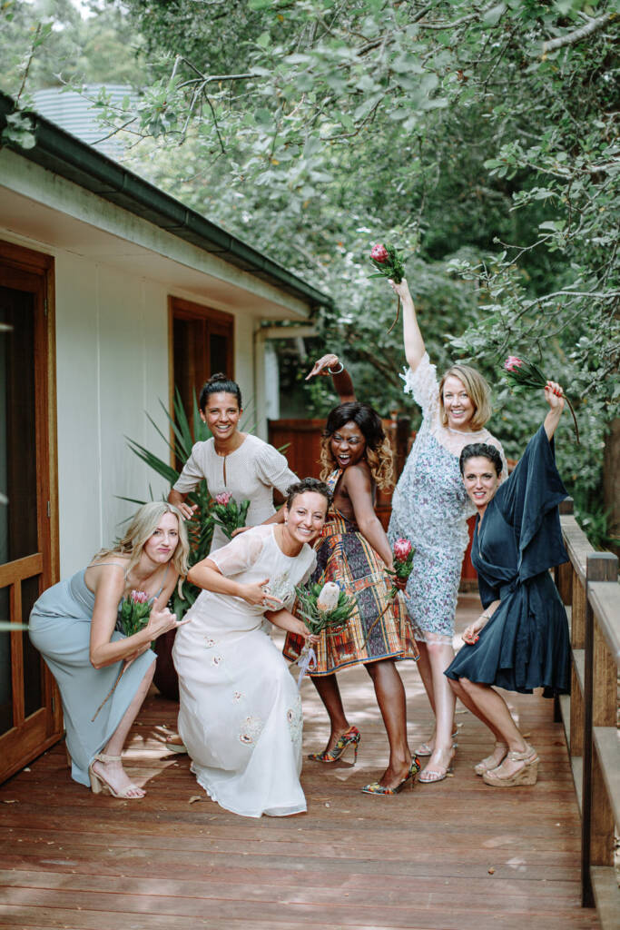 Sarah and five attendants pose playfully with bouquets on the verandah at Strathvea.