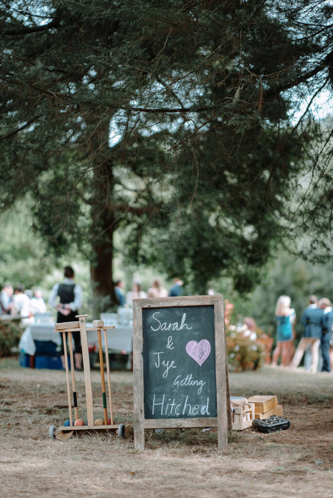 Sarah and Jye's chalkboard sign stands beside croquet equipment in the garden at Strathvea.