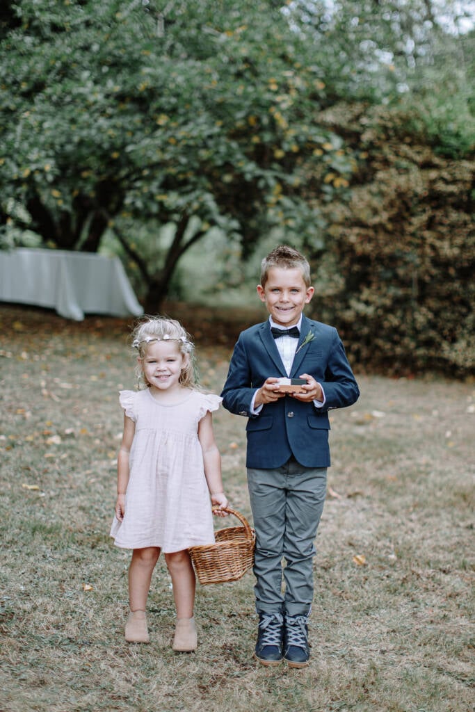 A flower girl and ring bearer pose with their basket and ring box on the lawn at Strathvea.