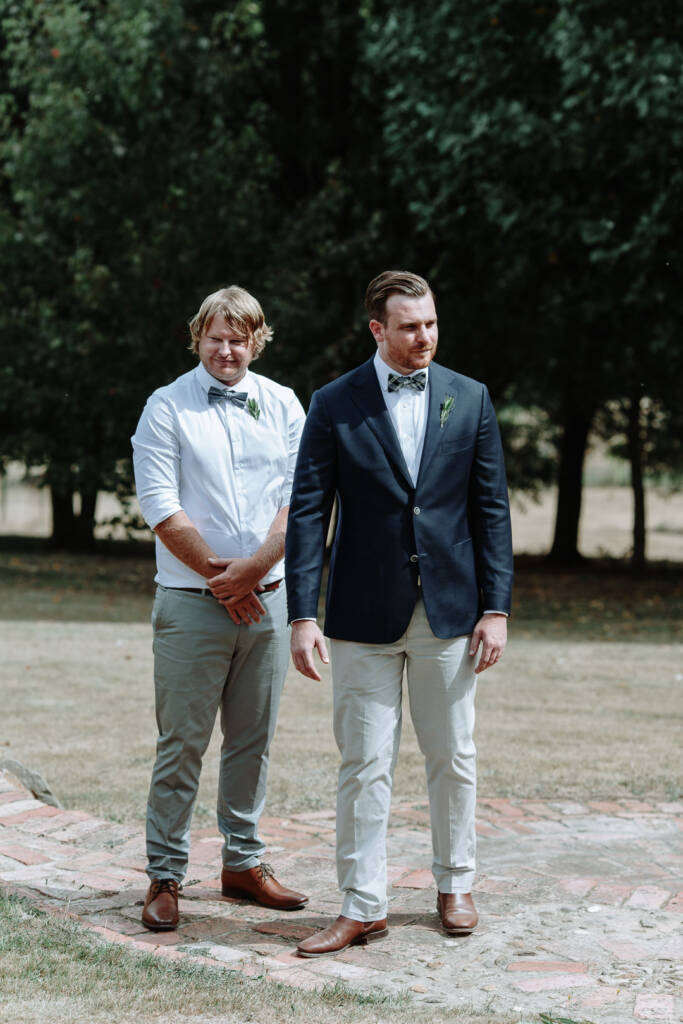 Jye and an attendant wait beside the garden ceremony space at Strathvea Guesthouse.