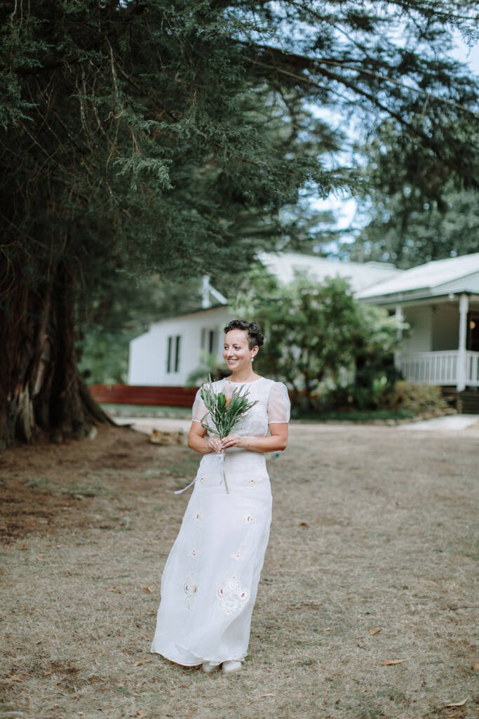Sarah smiles with her banksia bouquet on the lawn in front of Strathvea in the Yarra Valley.