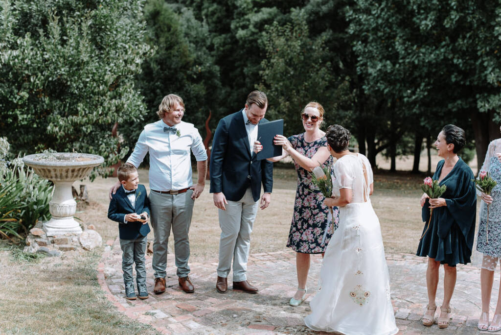 The celebrant raises a folder beside the smiling couple at Strathvea.