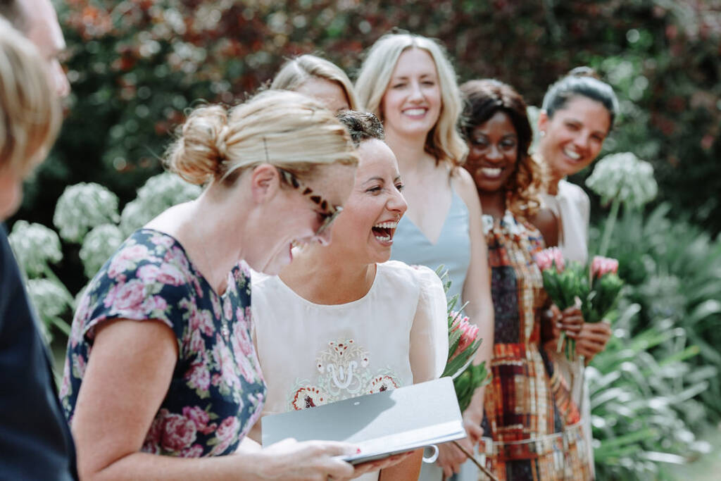 Sarah laughs beside the celebrant, with attendants behind her at Strathvea Guesthouse.