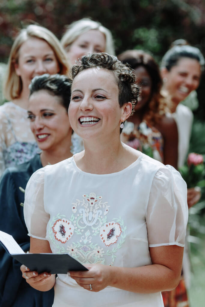 Sarah smiles while holding her ceremony booklet at Strathvea Guesthouse.