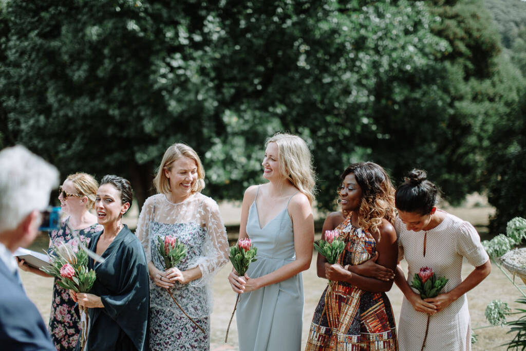 Five attendants watch the garden ceremony at Strathvea, holding their bouquets.