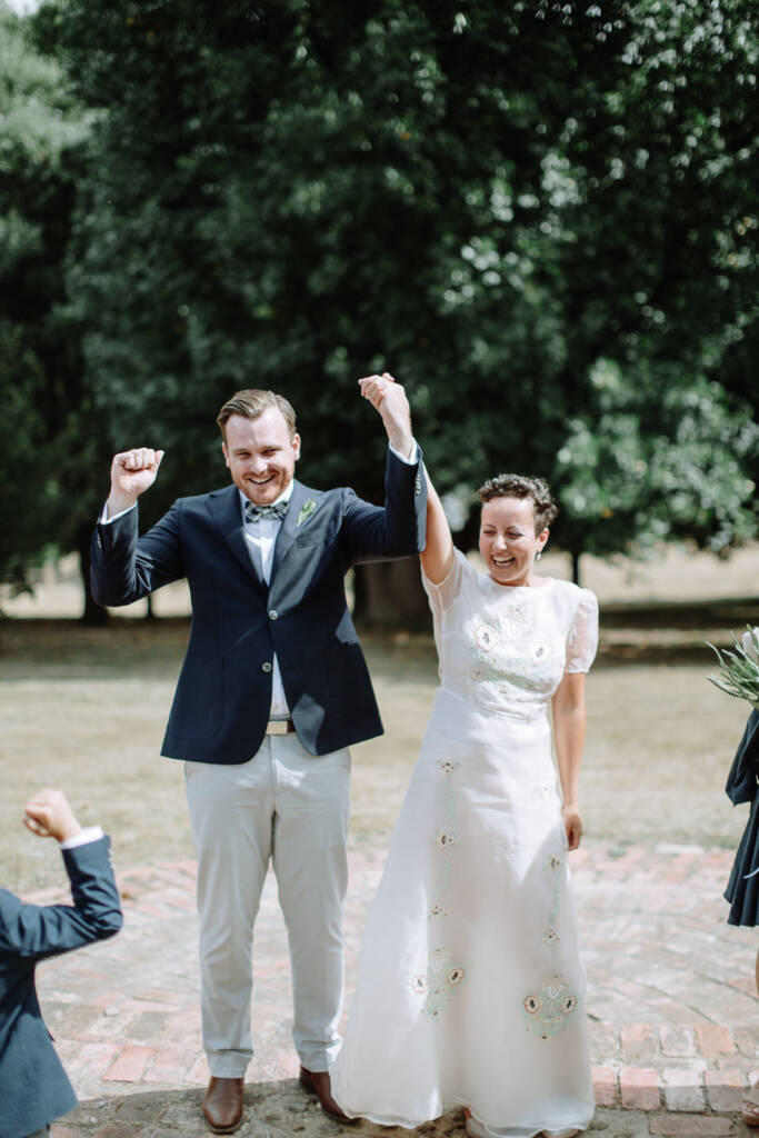 Sarah and Jye raise their joined hands at the end of their garden ceremony at Strathvea Guesthouse.