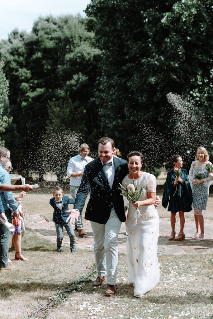 Confetti falls around Sarah and Jye as they walk past guests at Strathvea Guesthouse.