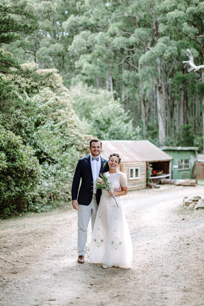 Sarah and Jye stand on the gravel beside a timber shed at Strathvea Guesthouse.