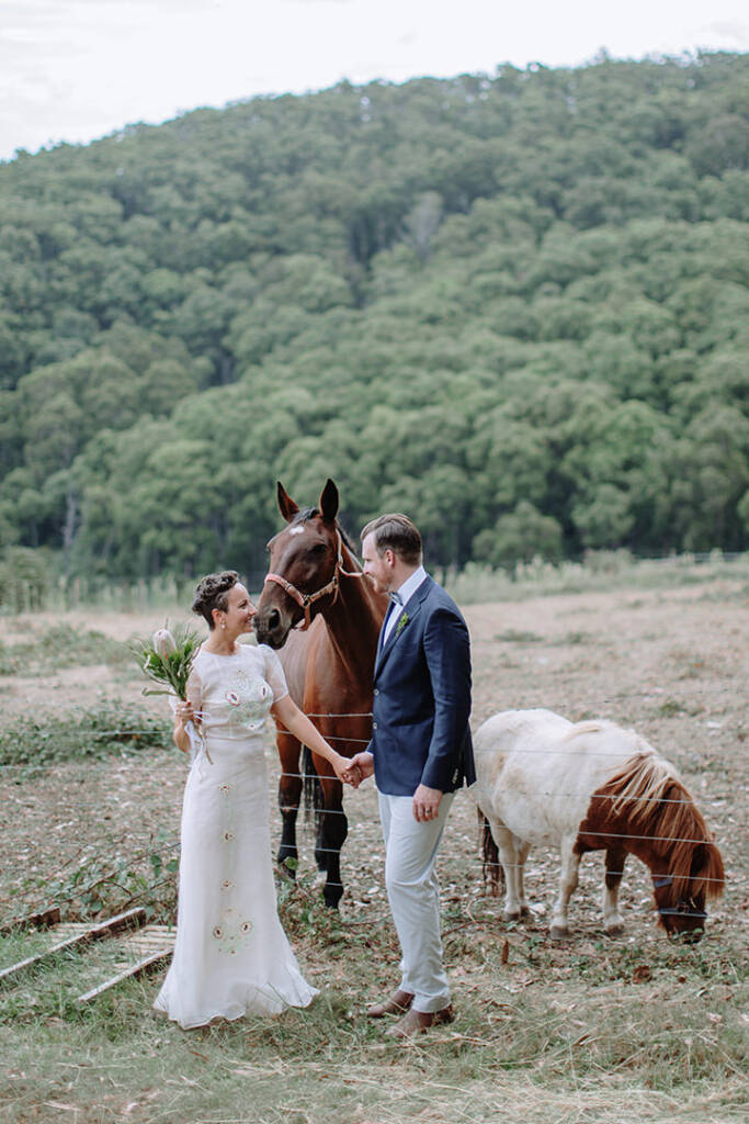 Sarah and Jye hold hands beside a horse and pony at Strathvea Guesthouse in the Yarra Valley.