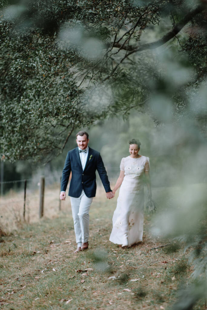 Sarah and Jye walk beside Strathvea Guesthouse's paddock during their country wedding portraits.