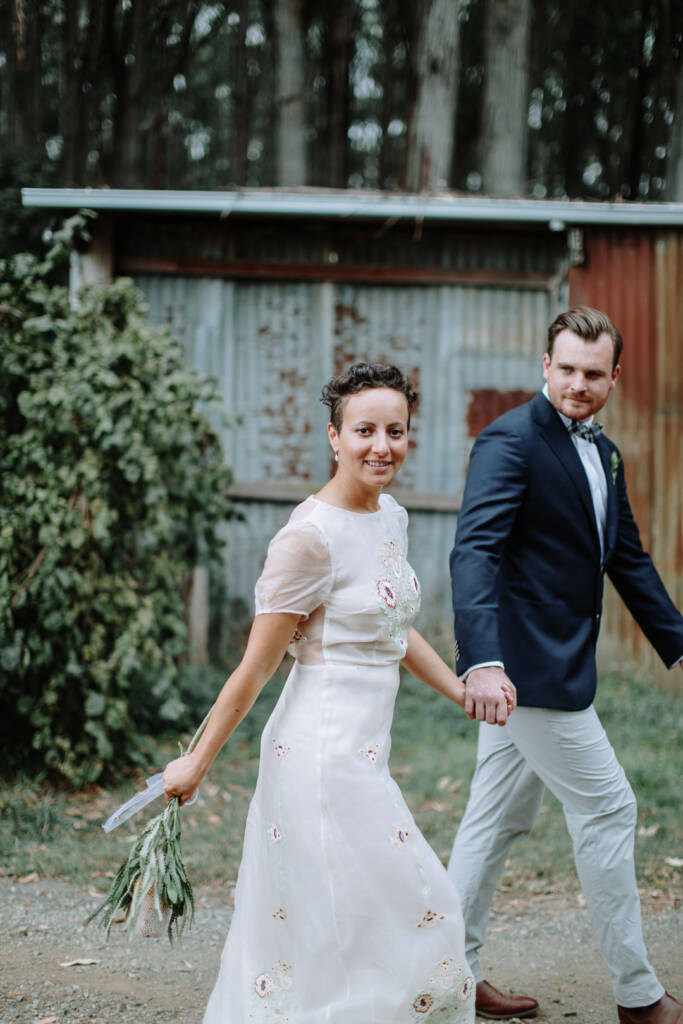 Sarah and Jye walk beside the corrugated shed at Strathvea Guesthouse.