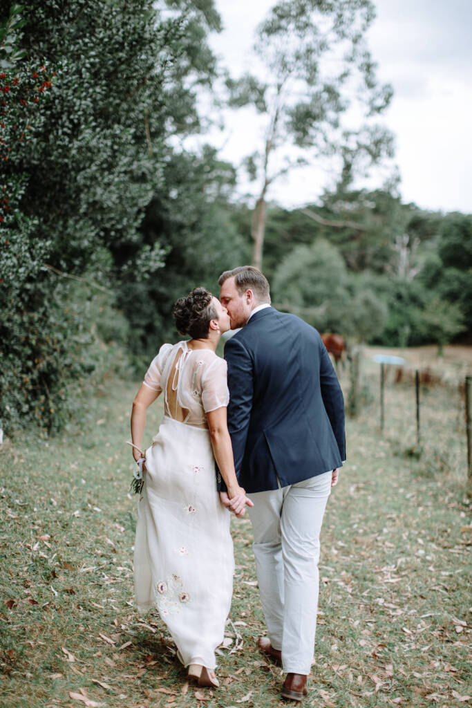 Sarah and Jye share a kiss beside the paddock at Strathvea, photographed from behind.